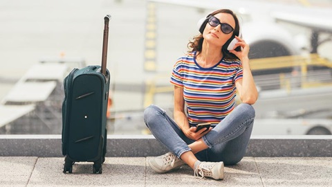 Een vrouw luistert naar muziek via haar hoofdtelefoon op de luchthaven.